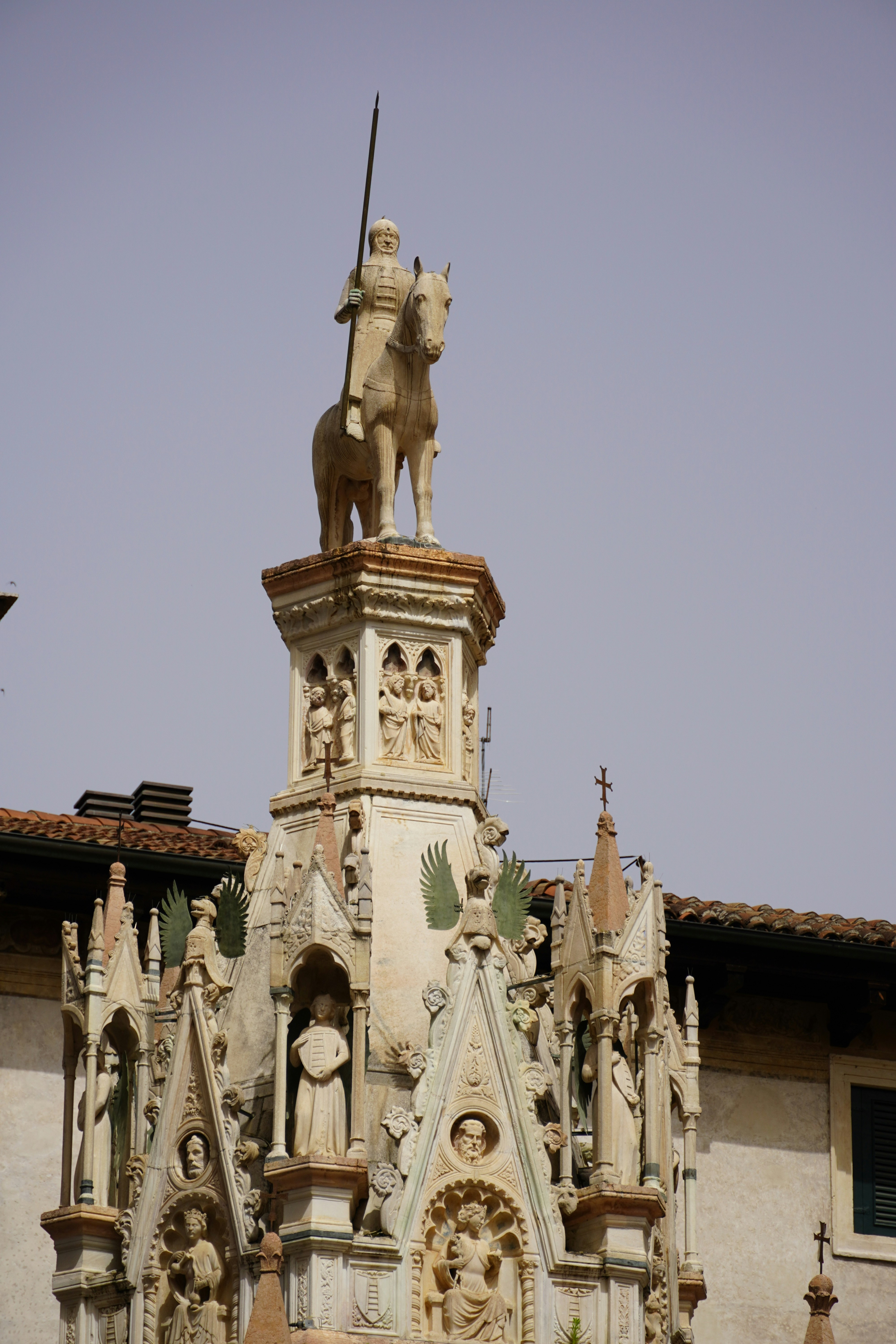 Bronze equestrian statue on a rooftop monument with a wreath against a clear sky, with classical architectural details.